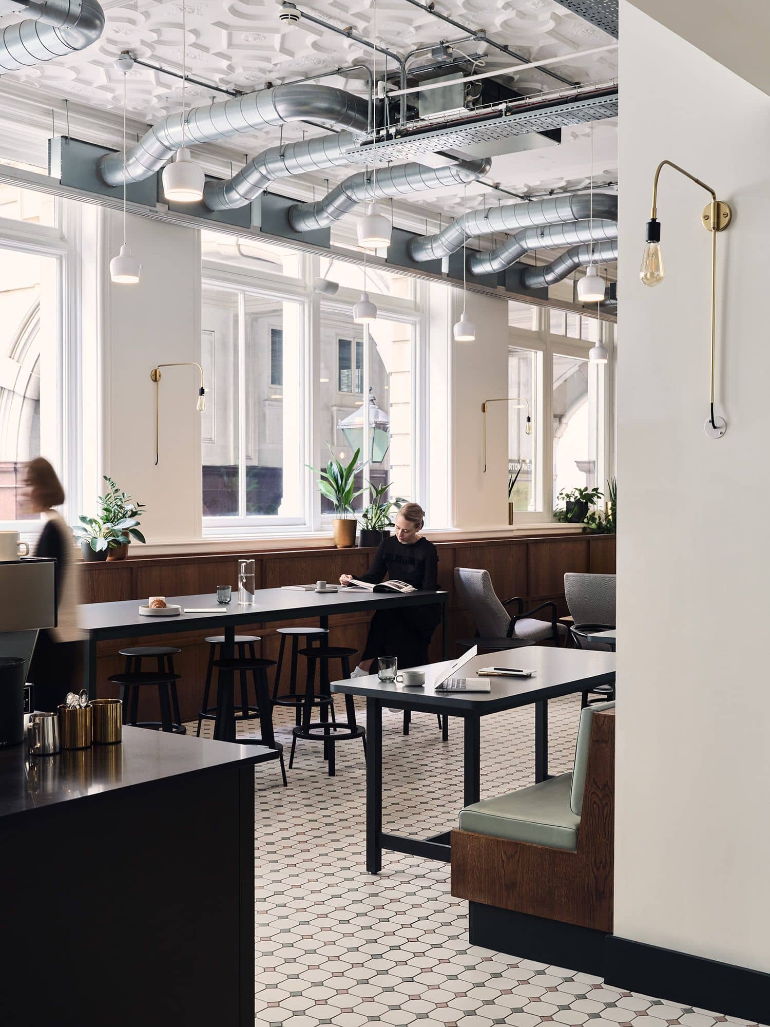 Woman reading at a dark wood table in the café at Warnford Court.