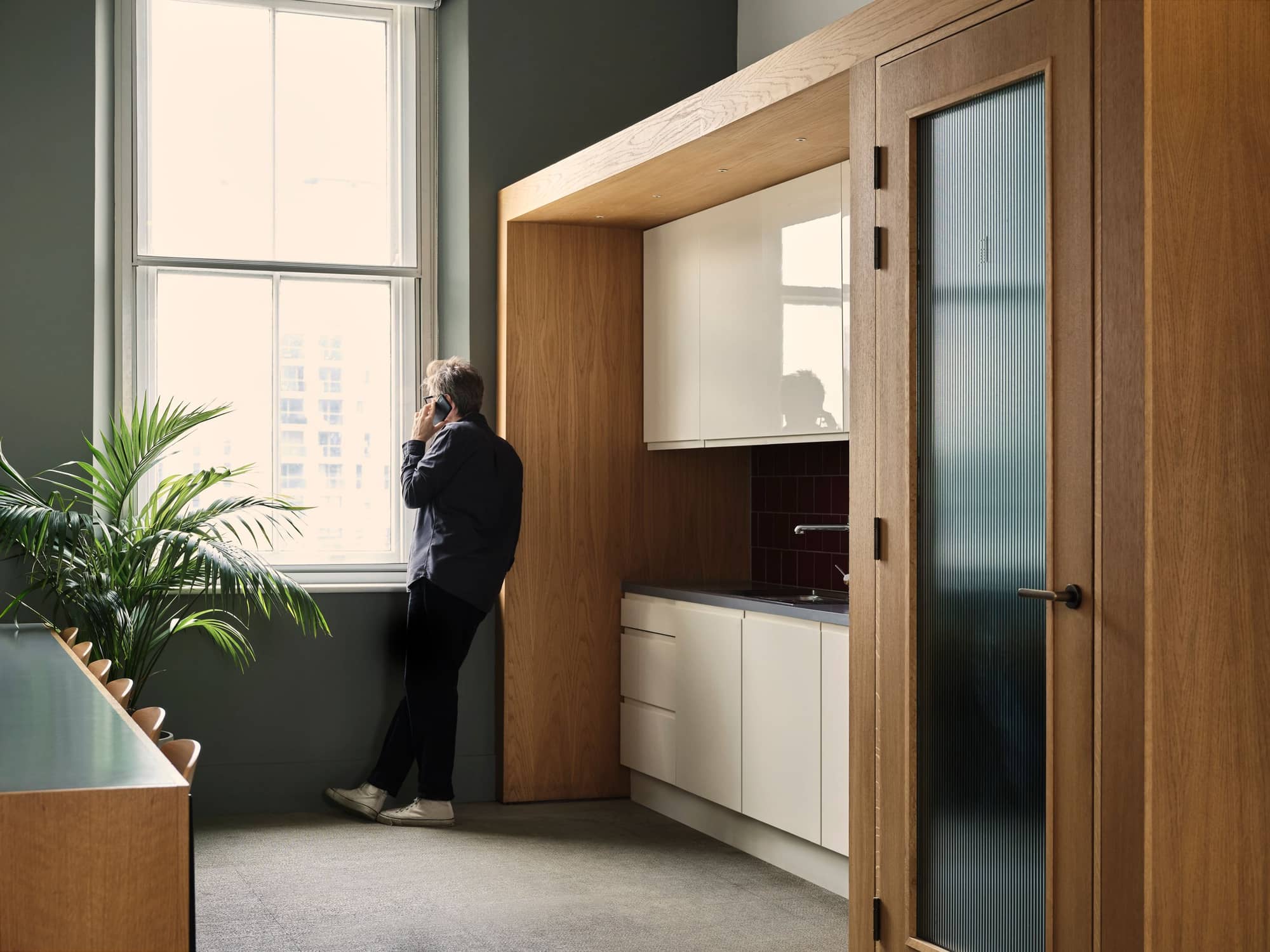 Man looking out the window and talking on the phone at 19 Eastbourne Terrace's kitchen.