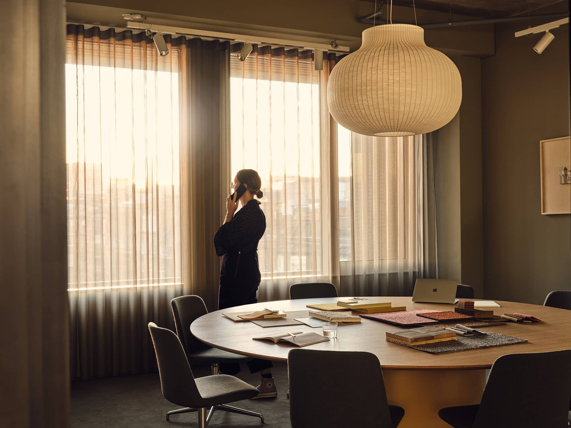 Woman looking out of the window and talking on the phone in a meeting room.