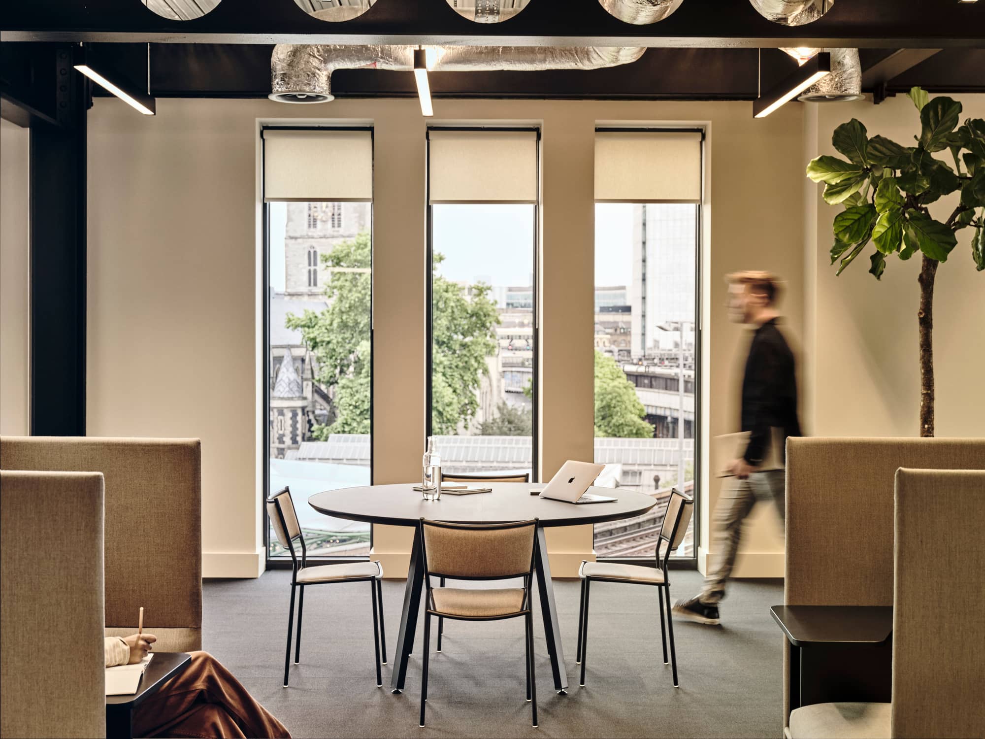 Man walking towards a round table with seats at Borough Yards.