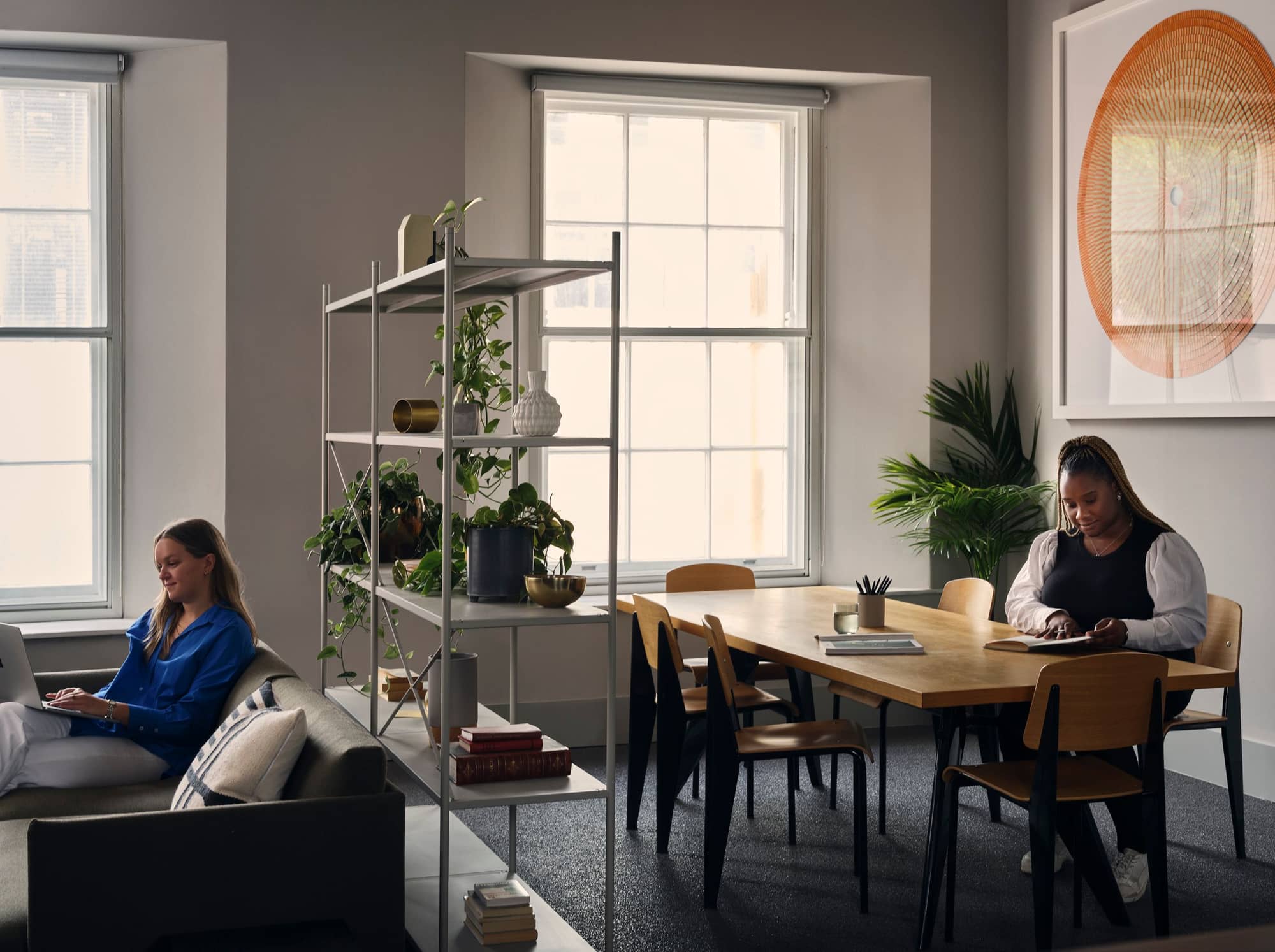 Two women using different areas of 19 Eastbourne Terrace's sleek coworking space.