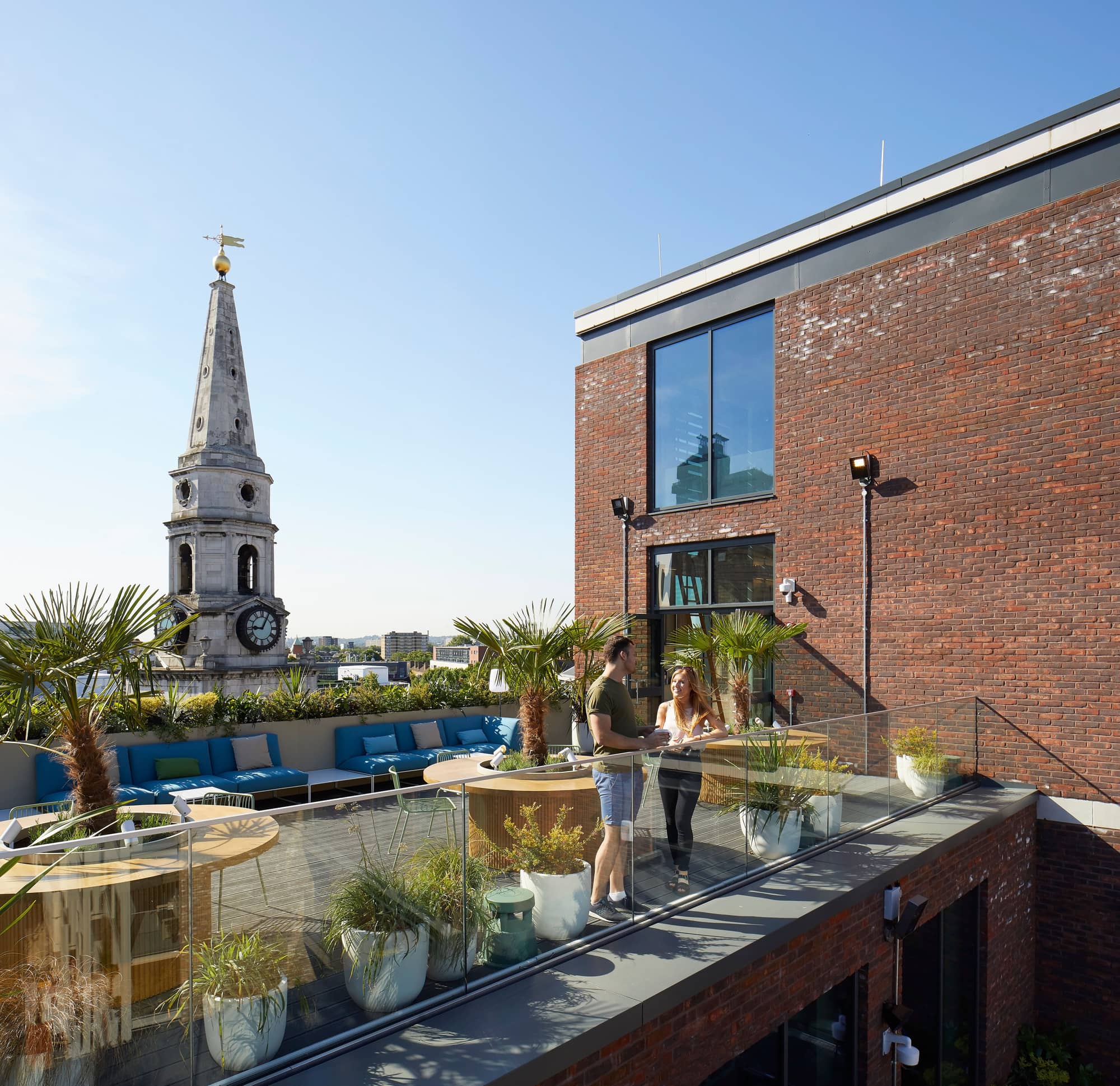 Man and woman chatting on a terrace with Horseguards Clock Tower behind them.