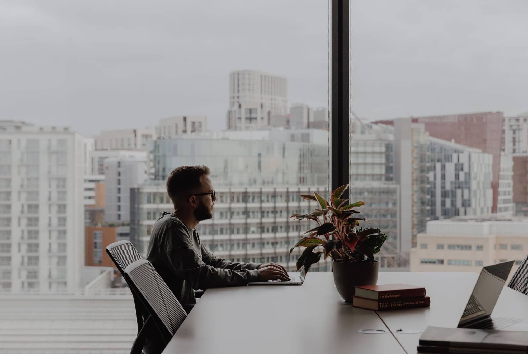 Man working on a laptop by the window with a panoramic view at 20 Eastbourne Terrace.