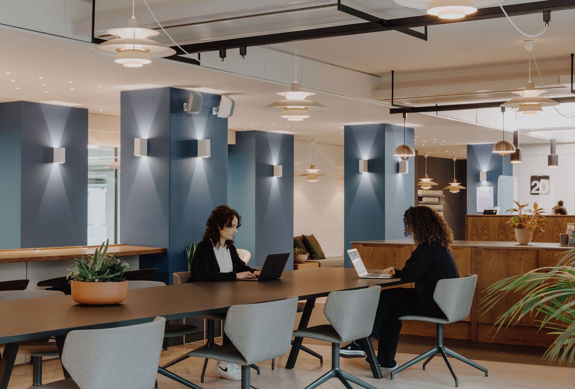 Two women working at a communal desk opposite each other at 20 Eastbourne Terrace.