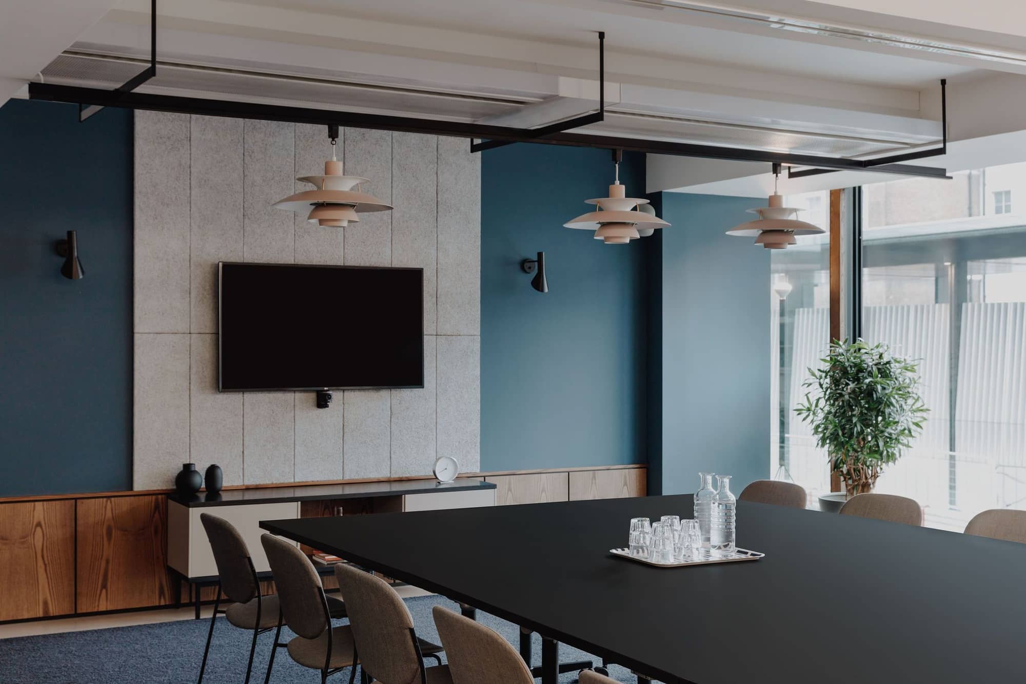Meeting room with mid-century modern furniture and a display screen at 20 Eastbourne Terrace.