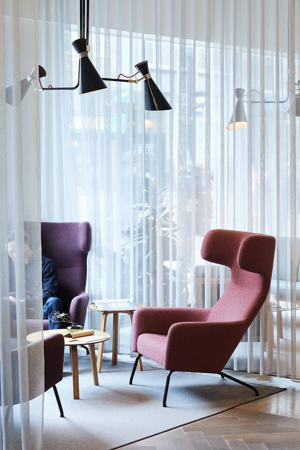 A cosy seating area with modern, high-backed armchairs in muted pink.